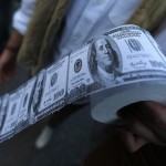 A demonstrator holds toilet paper made from fake US dollars during a protest against Turkey's Prime Minister Tayyip Erdogan and his ruling Ak Party government in Ankara