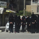 Female school students wearing a full veil (niqab) walk along a street in the northern province of Raqqa