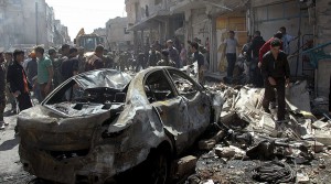 People gather at the site of two car bomb attacks at al-Abassia roundabout in Homs