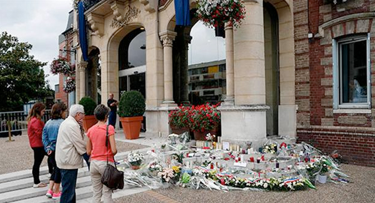 People gather to pay their respects at the makeshift memorial in front of the city hall after closed to the church where an hostage taking left a priest dead the day before in Saint-Etienne-du-Rouvray, Normandy, France, Wednesday, July 27, 2016. AP photo