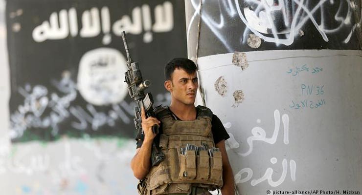 A member of Iraqi counterterrorism forces stands guard near graffiti supportive of the "Islamic State" after expelling the group from Fallujah